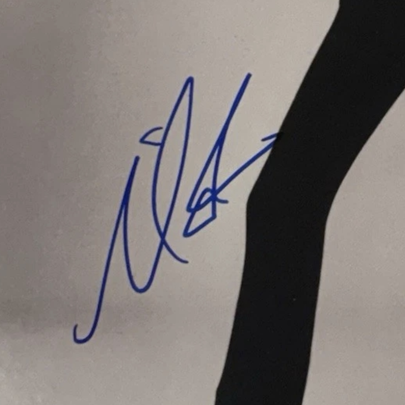A Mariah Carey signature in blue dye marker on a printed photograph, with the underlying print faintly visible through the stroke.