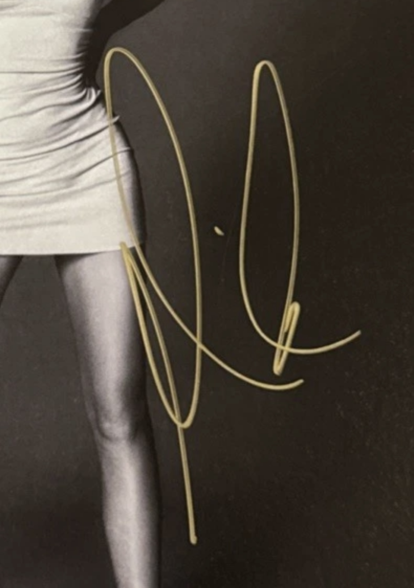 A Mariah Carey signature in gold or metallic marker on a printed black-and-white photograph.