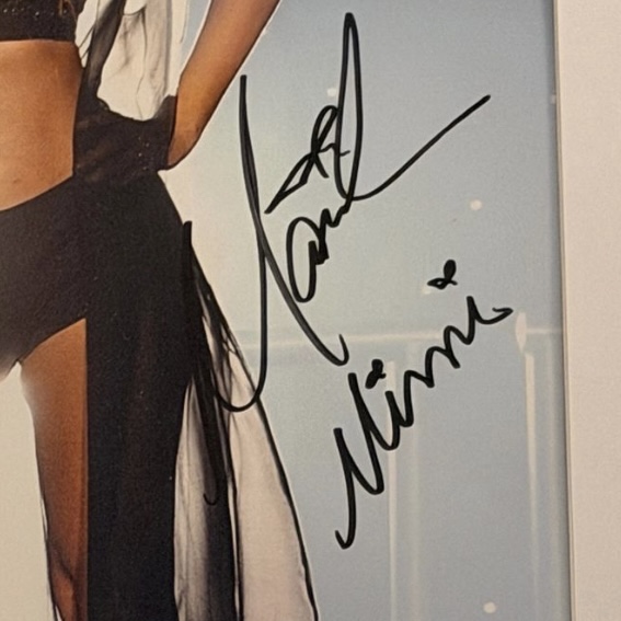 A framed photograph signed with the abbreviated Mariah Carey name and, on a second line below it, Mimi written separately.