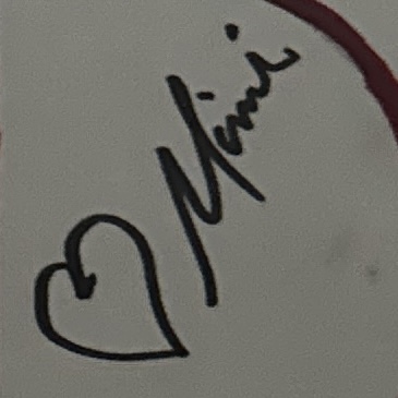 The word Mimi written in dark marker with a small heart beside it on a light card.