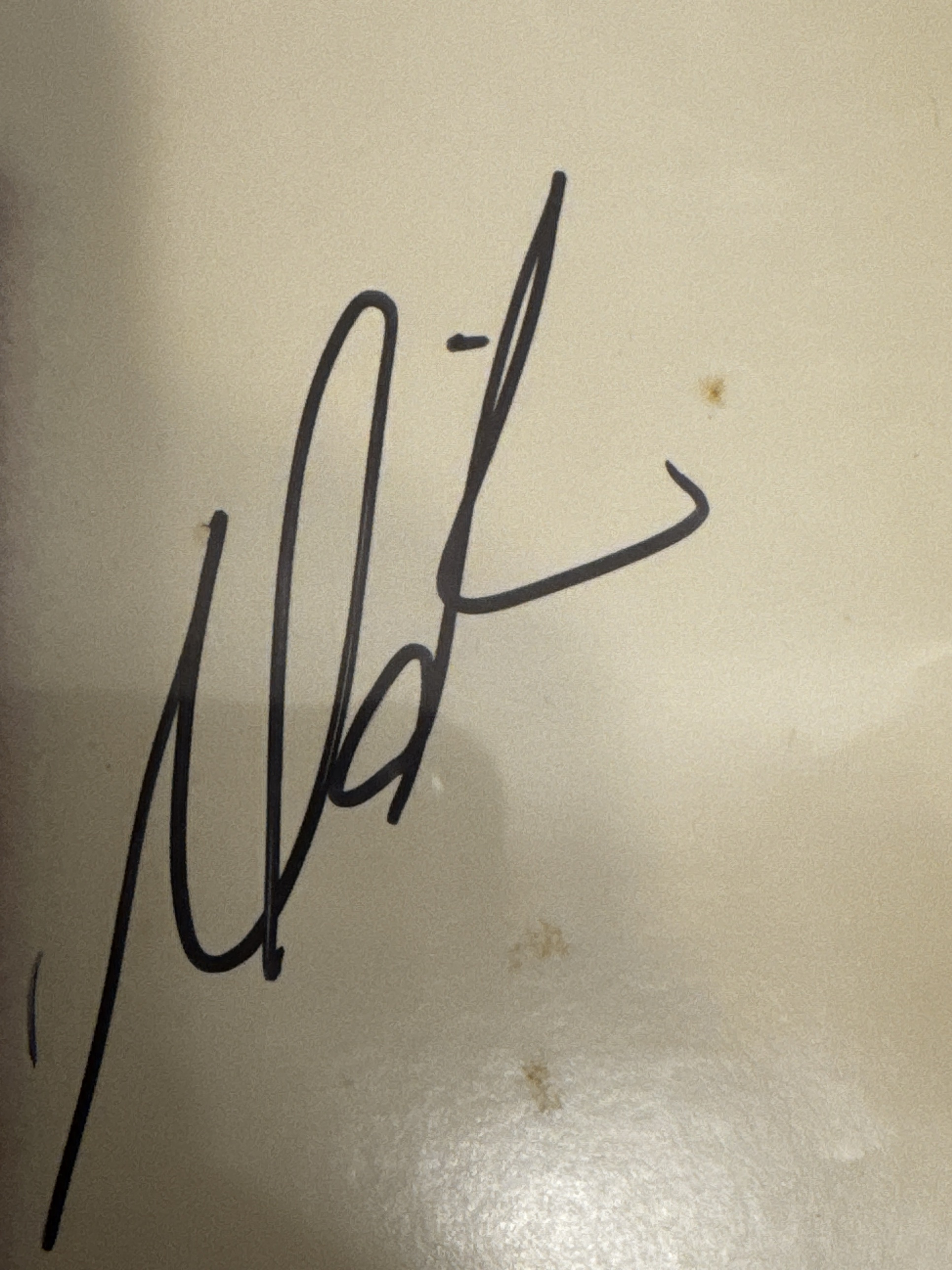Two Mariah Carey signatures in dark marker on glossy printed surfaces, one larger and one more compact.